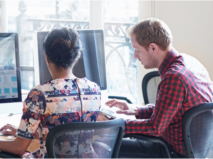 Over the shoulder shot of a seated people working in front of monitors.